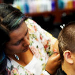 Stylist shaving design in woman's hair